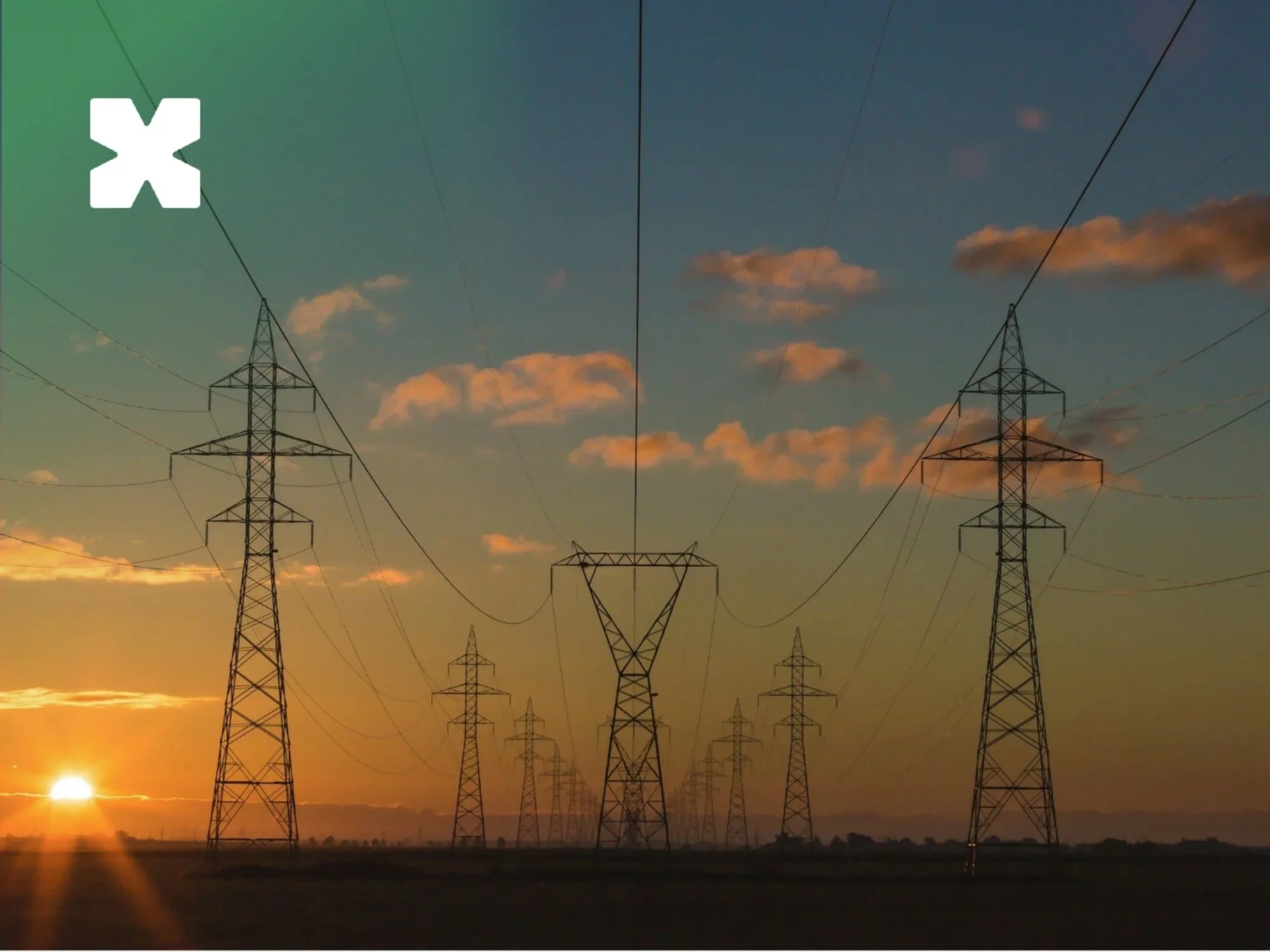 High-voltage transmission towers silhouetted against an orange sunset.